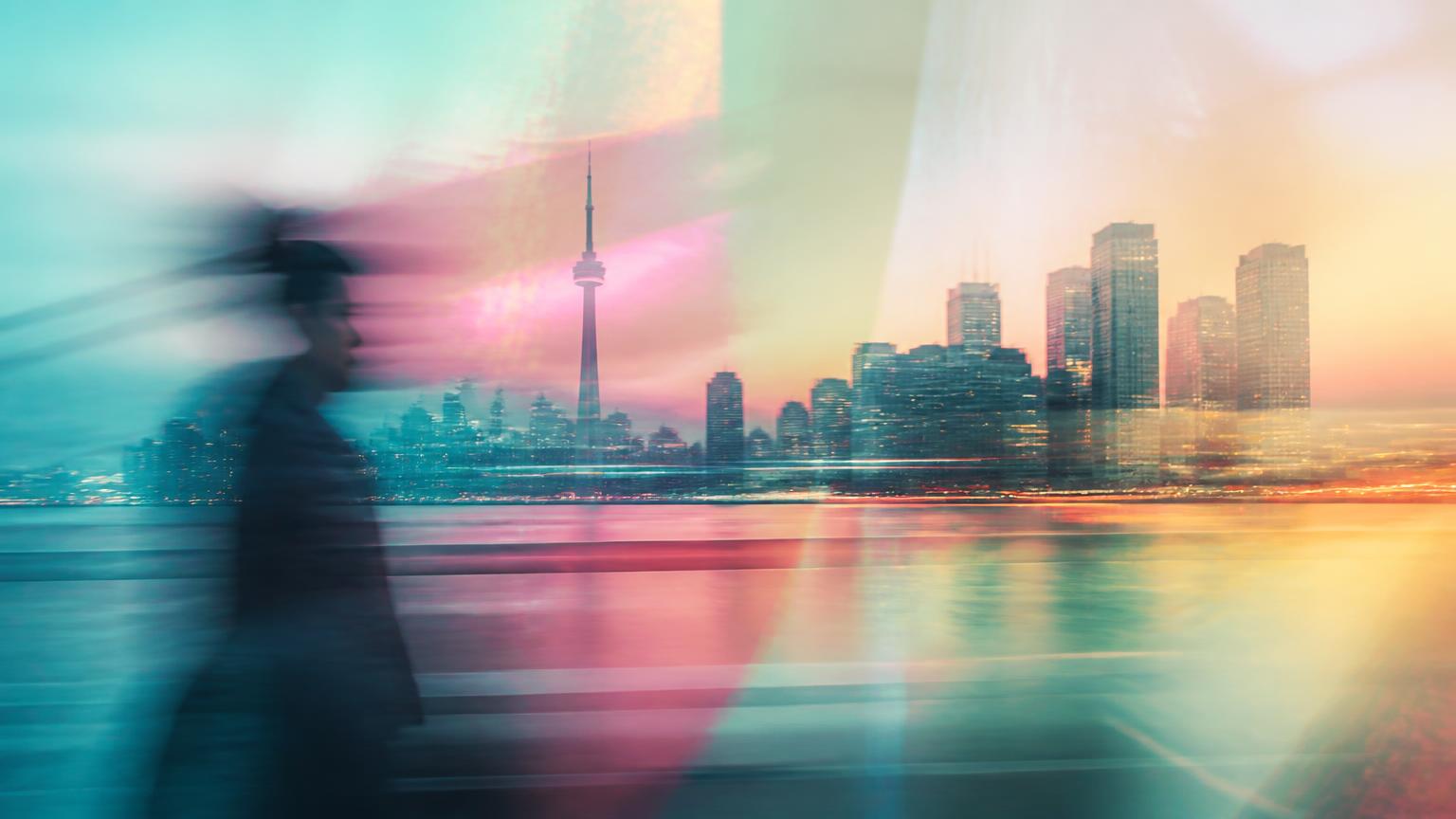 Long-exposure Canadian city skyline at dusk with a blurred passer-by under teal and pink gradient light